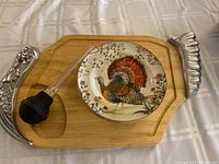 Carving baster with decorative silver-tone metal ends and Griffon wood carving board with serving plate on top