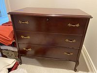 Front view of the cedar chest showing three drawers with brass handles and polished dark wood finish.