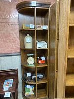 Full view of the wooden corner cabinet shelf with multiple shelves and vertical dividers showing the empty shelves and wood grain finish.