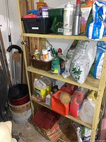 Garage shelving unit containing garden chemicals, fertilizers, seed packets, and containers including spray bottles and jugs.
