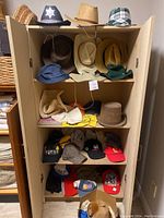 Multiple shelves of a wooden cabinet filled with various men's and women's hats of different styles including cowboy hats, fedoras, fabric hats, and baseball caps.