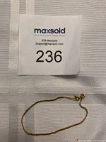 Full view of delicate gold bracelet laid flat on fabric, showing overall length and condition