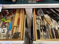 Top-down photo of two drawers with various kitchen utensils including wooden rolling pins, spatulas, and knives.