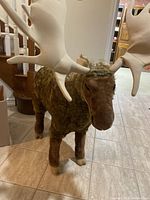 Front view of large plush moose showing head, antlers, legs, and textured body.