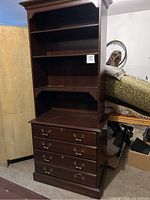 Full view of dark cherry hutch stacked atop matching four-drawer filing cabinet in garage setting