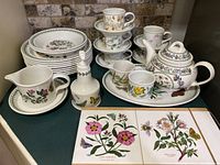 Full view of the dish set showing stacked plates, bowls, teacups with saucers, teapot on platter, cheese board, and soap pump.