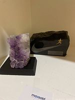 Amethyst crystal cluster and Nike rock decor award displayed side by side on a flat surface.
