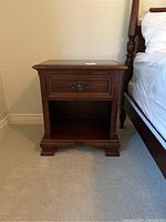 Full front view of the cherry wood night stand showing one drawer with dark metal handle and an open bottom shelf.