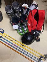 Overview of the ski boots, ski poles, helmet, and ski bag arranged on floor
