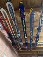 Multiple pairs of skis stored on red wall-mounted racks