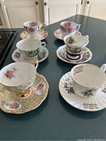 Photo showing all six teacups with matching saucers displayed on a kitchen countertop.