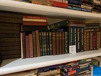 Shelf of vintage hardcover books with a Macbeth book on top, various classic literature volumes, and a Tolkien box set.
