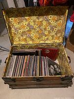 Open decorative wooden trunk lined with floral vinyl, filled with vinyl LP records showing spines and some front covers.