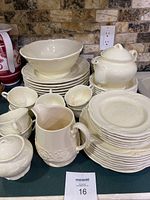 Photo showing multiple plates stacked along with teacups, creamer, sugar bowl, and a large serving bowl.