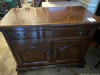 Front view of the dark wood sideboard with two drawers and two doors with matching metal handles.