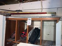 Overview of wooden shelf with Bosch and Craftsman jigsaws and assorted metal yardsticks and levels placed on top.