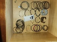 Top view of a wooden drawer containing multiple bracelets and bangles arranged side by side, showing variety in styles and colors.