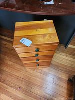Front view of the four drawer wood cabinet showing natural wood stripes and green round drawer pulls.
