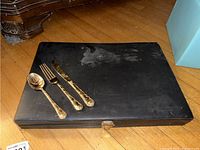 Closed black case containing the flatware set with latch visible