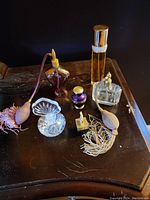 Wide angle view of all perfume bottles arranged on wooden surface, showing variety of shapes and atomizers with tassels
