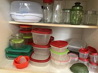 Shelves showing assorted plastic food storage containers in various colors and sizes along with clear glass jars with lids