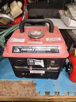 Top view of generator showing control panel, brand label, carrying handle, fuel cap and warning labels.