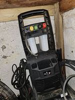 Full view of the pressure washer showing the handle, detergent tanks, and colored nozzle tips attached.