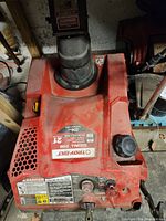 Top view showing brand label, engine size and model details, red housing with chute.