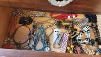 Top-down view of multiple necklaces laid out showing variety of materials, colors, and styles.