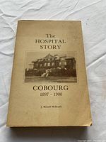Front cover of the vintage historical book 'The Hospital Story Cobourg 1897 - 1980' with author J. Russell Melraith. Shows the book's condition and cover image of the hospital building.
