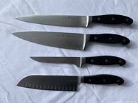 All four knives laid out on white cloth