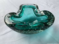 Image of a mid-century modern style vintage Murano glass bowl, green with silver flecks and bubbles, organic flowing shape with three inward curves.