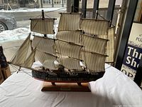 Front and side view showing full ship model with sails and rigging on wooden base.