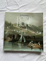 Photo of the front cover showing the book titled 'Port Hope: A History' with a vintage style painting of a harbor town scene.