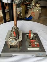 Full front view of the Wilesco D8 steam engine model on a white cloth, showing the boiler, chimney, flywheel, and base with the Wilesco logo.