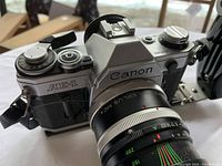 Canon AE-1 35mm film camera body with Takumar lens attached, showing branding and top dials