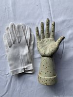 Photo showing the cast iron hand glove display next to a white glove on a white cloth background