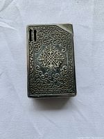 Front view of the lighter showing intricate flame crest design on the metal case.
