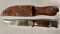 Photo showing the fixed blade knife with stag handle alongside the leather sheath, highlighting overall wear and condition.
