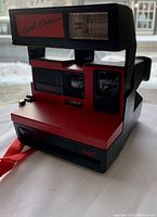 Front three-quarter view of the red and black Polaroid 600 Cool Cam land camera showing design details and branding.