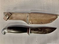 Full view of the knife and leather sheath laying flat, showing the blade and handle details.