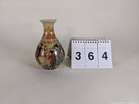 Full front view of the vase next to number 364 on display stand for scale, showing overall proportions and condition.