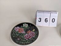 Top angle view of the floral design showing detailed pink and red flowers with green leaves and Chinese characters on a black background.