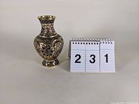 Photo of small cloisonné-style enameled vase alongside number cards for scale reference.