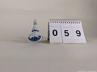 Porcelain blue and white snuff bottle shown next to numbering cards '059' for scale and identification
