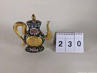 Front view of cloisonne-style enameled coffee pot showing floral patterns and gold-tone decoration