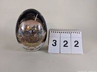 Front view of the gilt decorated Limoges porcelain egg with bird scene and gold accents.