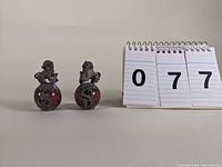 Pair of Chinese Fu Dogs sitting on red stone spheres with metal decorative mounts shown with lot number.