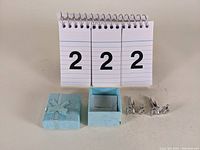 Pair of dragon cufflinks with blue gift box and number display in background.