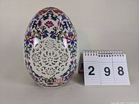 Front view of pierced porcelain ostrich egg with detailed floral patterns and pierced design center.
